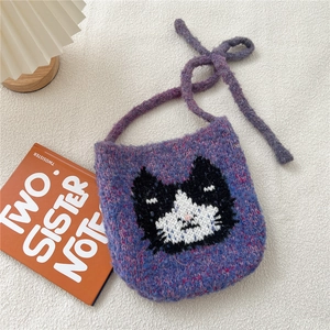 Détail macro du sac en tricot violet avec motif chat tissé et texture de laine douce