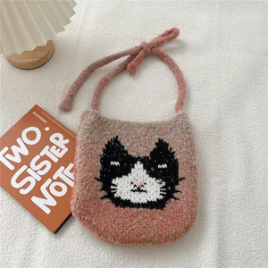 Détail du sac bandoulière en maille rose avec jacquard de chat sur fond blanc doux