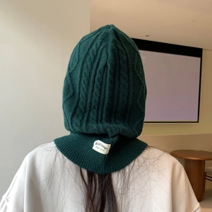 Rear view of dark green knitted balaclava showing thick cable knit texture and logo label