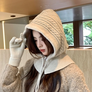 Detail of cream cable-knit balaclava scarf and matching gloves in soft winter lighting