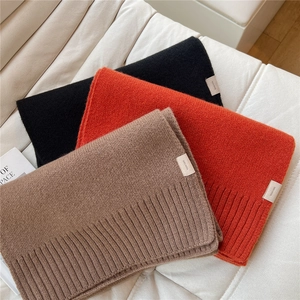 Dettaglio di sciarpe in lana nera, arancione e beige con trama a maglia a coste fini
