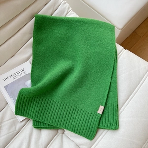 Primo piano di una sciarpa verde al 100% lana con bordi a coste e trama morbida
