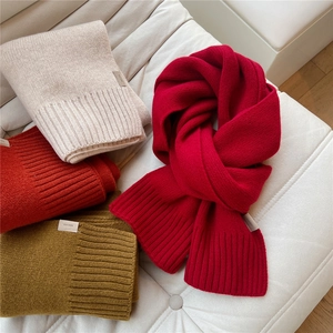 Sciarpe spesse in lana 100% a costine beige, verdi e rosse su sfondo in pelle bianca