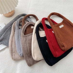 Minimalist knit tote bags in multiple colors arranged on a textured white background