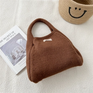 Close-up of brown knit tote bag with woven texture and white logo label detail