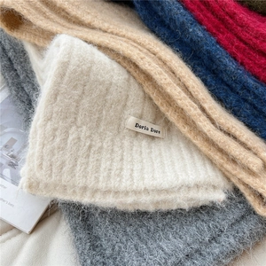 Detail of soft chunky knit texture on solid color warm winter scarves stacked with labels