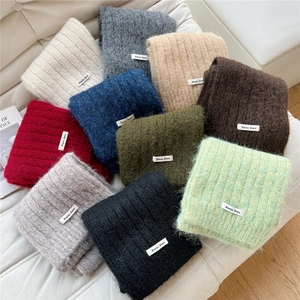Thick knit winter scarves in multiple solid colors with soft mohair texture on white leather