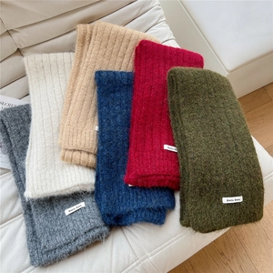 Close-up of soft knitted scarf textures in multiple colors and woven brand label