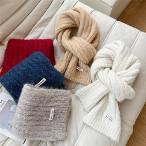 Detail of assorted chunky knit scarves in various colors with stylish brand woven labels