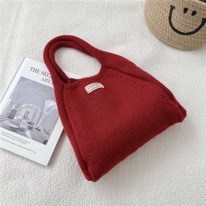 Detailed macro view of dark red knitted tote bag with woven texture and white logo label