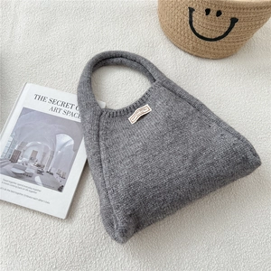 Detailed texture of grey knit tote bag with minimalist white label on soft fabric