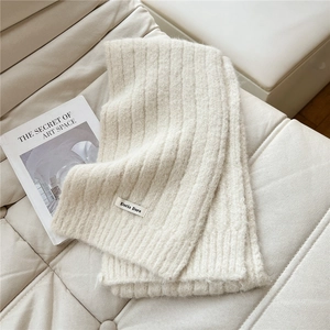 Detail of cream knit scarf featuring ribbed texture and a minimalist brand logo label