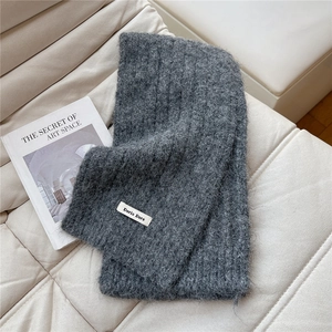 Close-up of dark grey ribbed knit scarf showing soft wool texture and fabric label