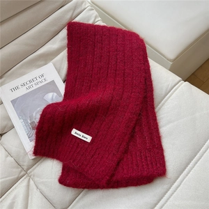 Detailed texture of thick dark red knitted scarf with a white woven label on top