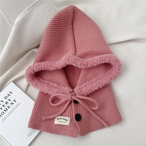 Detail of pink knitted balaclava with fleece trim, buttons, and drawstrings on fabric