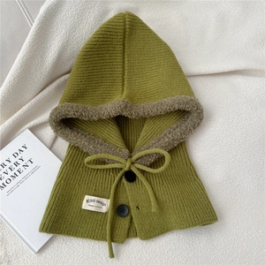 Detail of green knit balaclava featuring faux fur trim, black buttons and drawstring tie