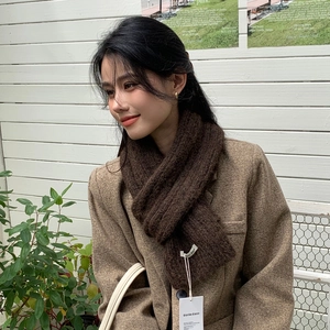 Detailed close-up of dark brown chunky knit scarf texture with a white brand tag