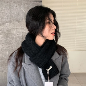 Detail of black thick knitted scarf with brand label worn on grey wool coat