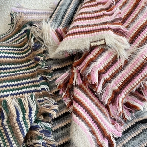 Close-up of striped knit scarf texture with long tassels and Jennie Wool fabric label