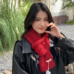 Close-up of fluffy red knitted scarf with brand label and tag on black leather jacket