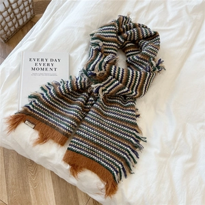 Close-up of wool blend striped scarf with brand tag and soft tassel fringe detail