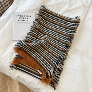 Detail shot of striped knit scarf with leather label and soft fringe tassels
