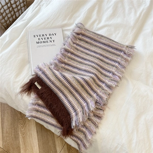 Detailed close-up of knit striped scarf with long fringes and plush faux fur trim