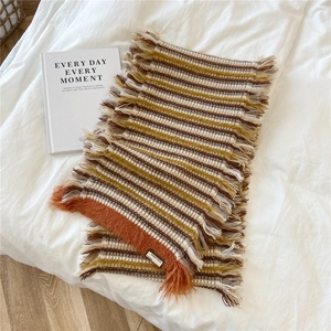 Detail of striped knitted scarf with wool texture, fringe edges and woven brand label