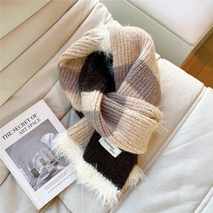Detail of knit scarf with brown color blocks and faux fur trim on white leather