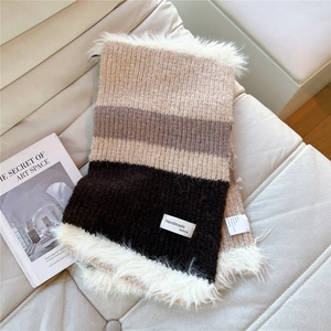 Detail of striped knitted scarf with faux fur trim and handmade fashion woven label