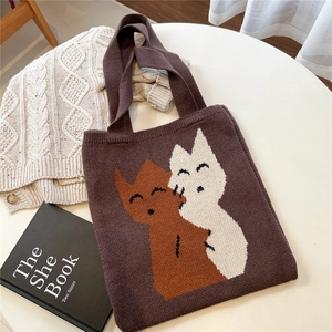 Détail d'un sac cabas en maille marron avec deux chats qui s'enlacent sur table
