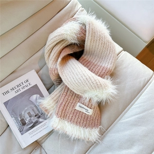 Detail of pink and white gradient knit scarf with soft faux fur tassels and woven label
