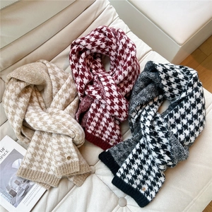 Close-up of knitted houndstooth scarves with fringes and elegant metal brand buckles