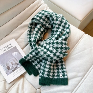 Detail of green and white houndstooth knit scarf with ribbed edge and metallic button