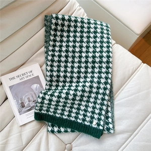Detail of green and white houndstooth knit scarf with ribbed edge and metal logo
