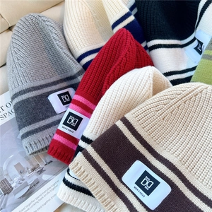 Detail shot of multi-colored striped knit beanies showing thick texture and woven labels