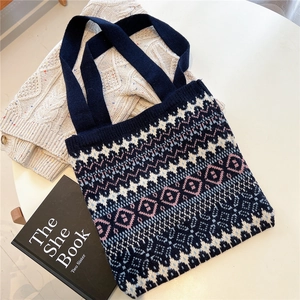 Detail of knitted tote bag with ethnic geometric patterns on a white tabletop