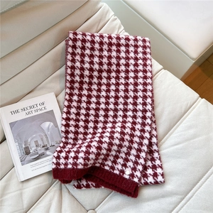 Detail of red and white houndstooth knit scarf with ribbed edge and metal button decor