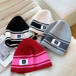 Striped ribbed knit beanies in four colors on a cozy sofa with high texture detail