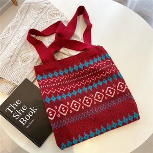 Detail of red knit tote bag with geometric rhombus patterns on a minimalist white desk