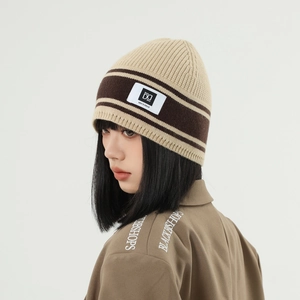 Detail view of khaki striped knit beanie with woven brand label and warm texture