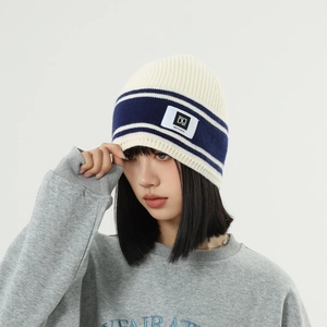 Close-up of striped knit beanie with Dore logo patch and soft ribbed wool texture