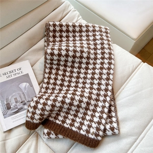 Close-up of brown houndstooth knitted scarf with ribbed edge on a cream leather sofa