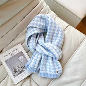 Detail of blue houndstooth knit scarf with metal button on a minimalist sofa