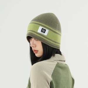 Close-up of olive green striped knit beanie with custom brand label and matching sweater