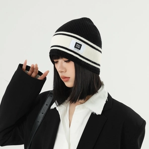 Detailed close-up of a black and white striped knit beanie featuring a stitched DG label