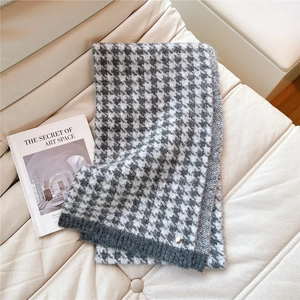 Detail of houndstooth scarf with gray knit edge and small gold button decoration