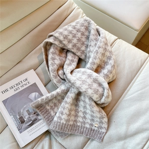 Detailed close-up of houndstooth knit scarf texture with a small metal logo detail