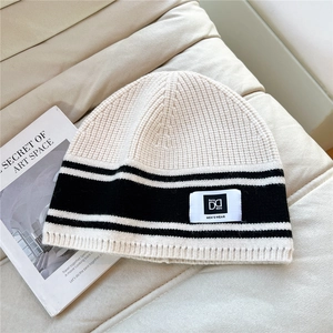 Detailed close-up of striped knit beanie with brand label on a soft textured background