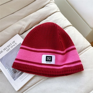 Detail of red and pink striped knit beanie with soft texture and vintage woven label